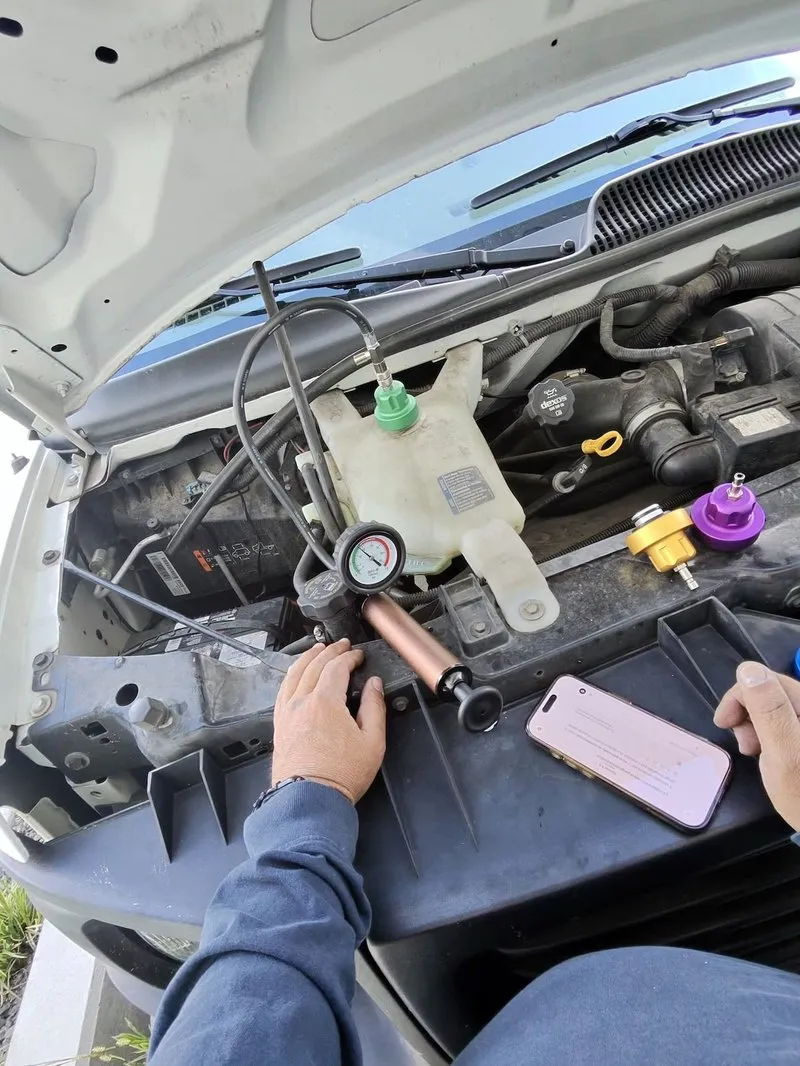 Certified mechanic running a coolant system pressure test on a GMC Savana engine in Kelowna